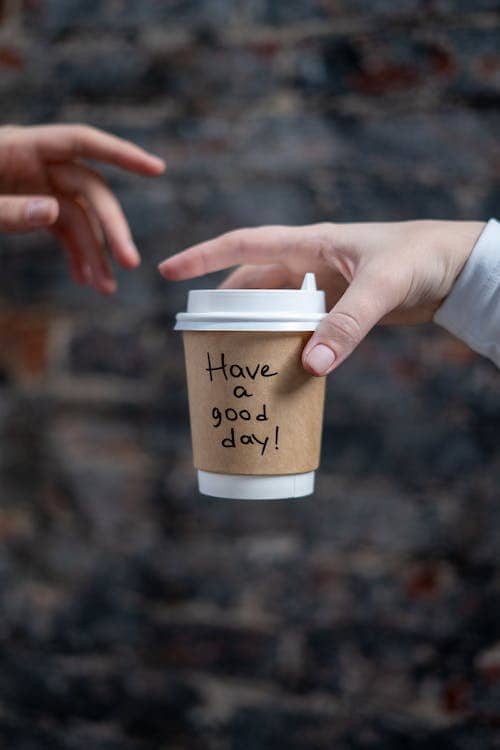 A hand with a cup labelled "have a good day" giving the cup to someone else
