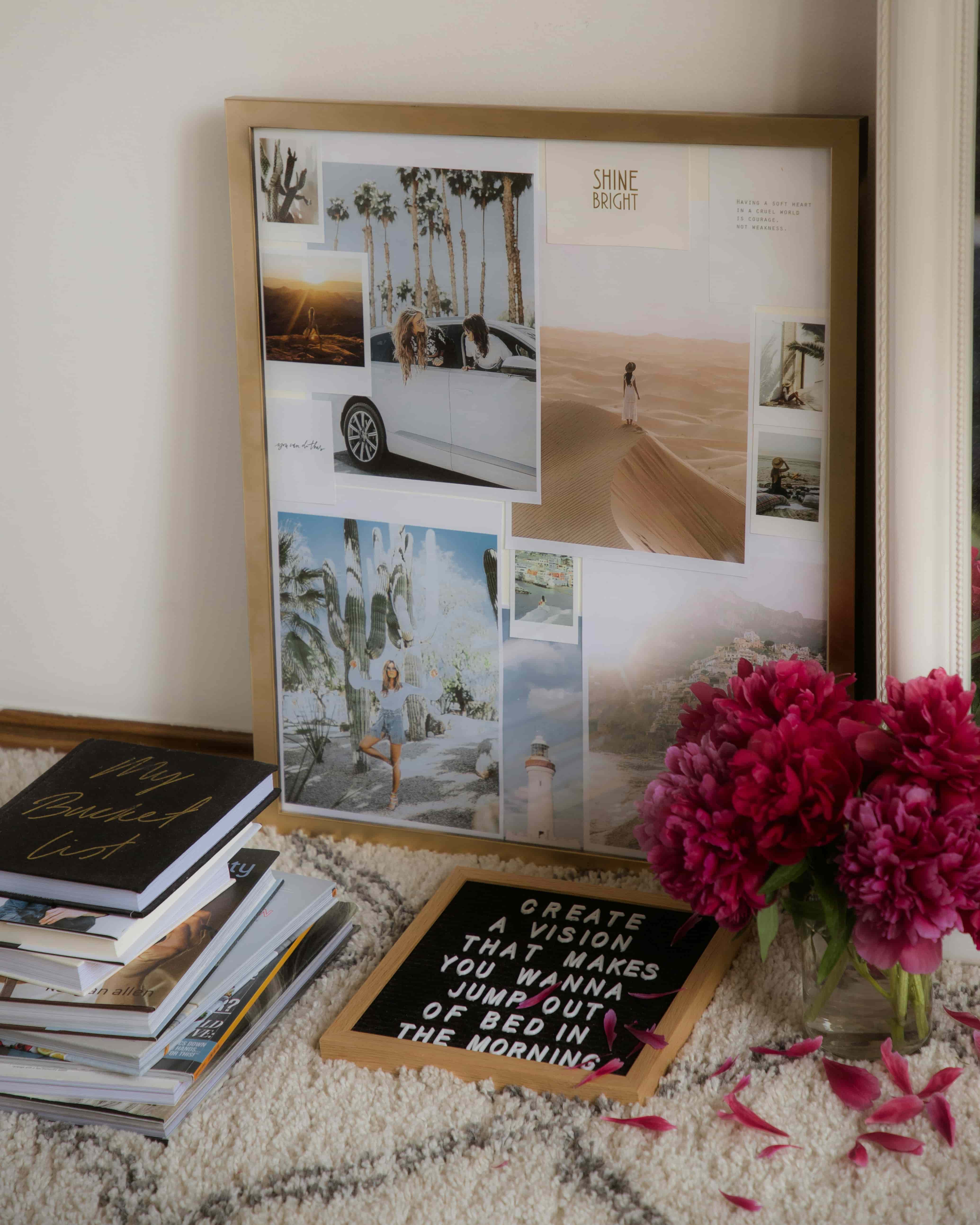 Vision board on the floor next to pink flowers, inspirational quotes, and a stack of books.