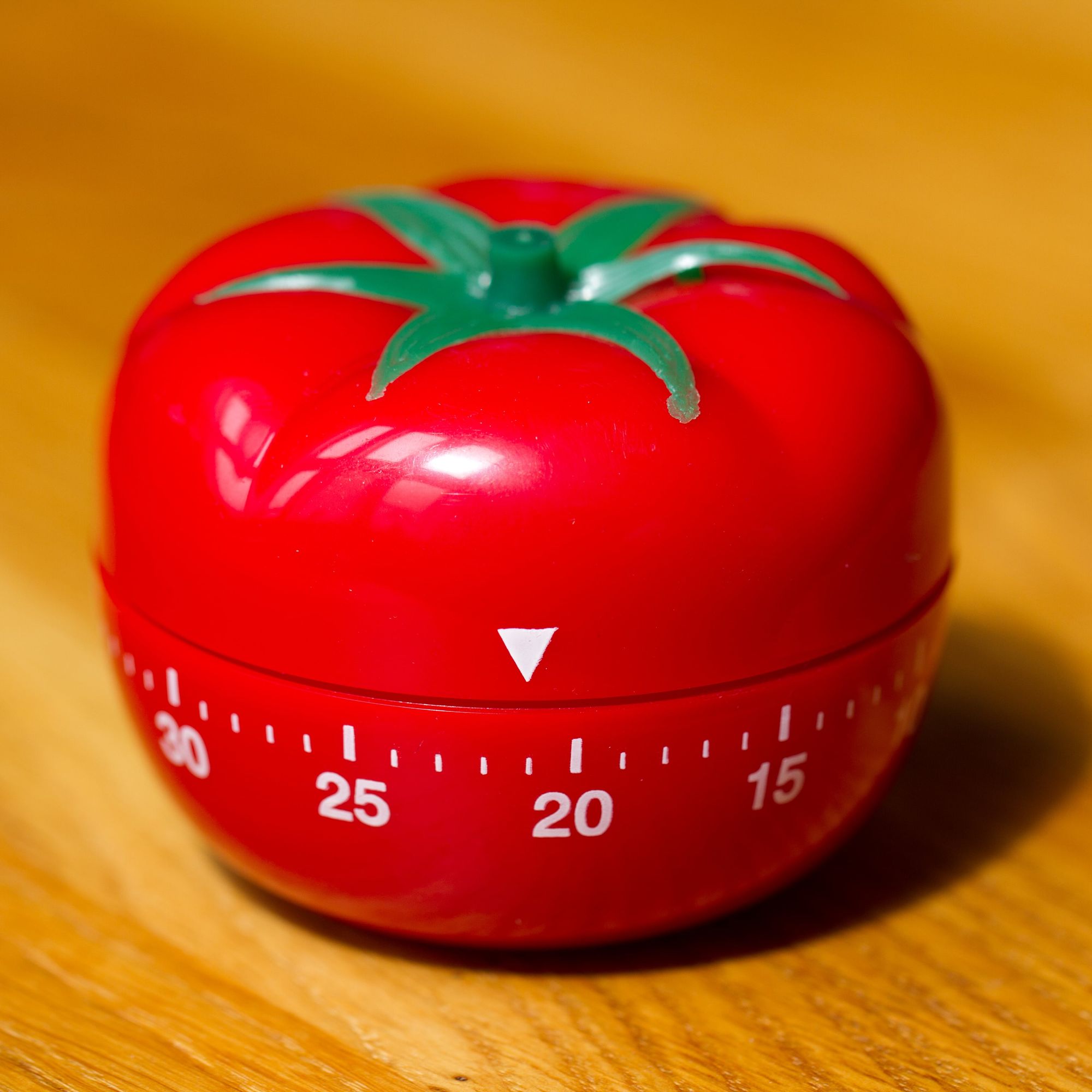 Tomato-shaped kitchen timer sitting on a wooden surface
